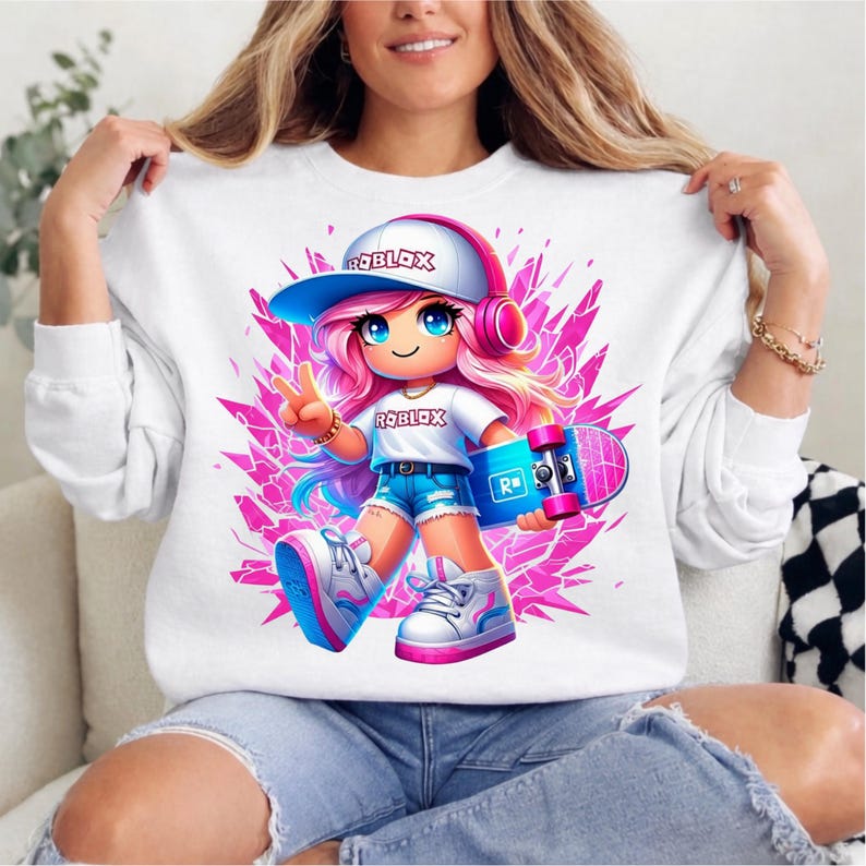 May include: White sweatshirt with a cartoon girl with pink hair, headphones, and a skateboard. The girl is wearing a hat and t-shirt with the word "ROBLOX". The background is a pink geometric design.