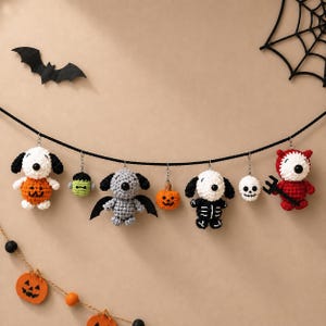 May include: A Halloween-themed garland featuring seven crocheted ornaments hanging from a black string. The ornaments include a dog in a pumpkin suit, a green monster head, a grey bat-dog, a small pumpkin, a skeleton-dog, a skull, and a red devil-dog.