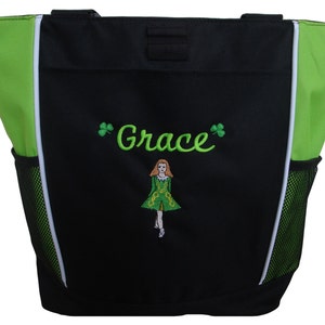 May include: Black and green tote bag with the name "Grace" embroidered in green script, along with shamrock accents. The bag features a white and green trim, a mesh side pocket, and an embroidered image of a girl in a green dress.