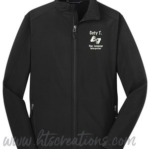 May include: Black softshell jacket with a zipper closure. The jacket has a white embroidered design that says "Coty T. Sign Language Interpreter" with a hand sign for the letter "I".