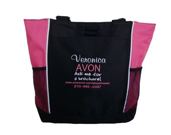 May include: Black tote bag with pink accents and a white zipper. The bag has a mesh pocket on each side. The bag is embroidered with the text "Veronica AVON Ask me for a brochure! www.youravon.com/taryashoward 210-845-0397"