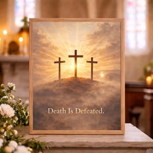 Puede incluir: Una impresión enmarcada que presenta tres cruces sobre un fondo de puesta de sol. La imagen tiene una paleta de colores cálidos con un efecto de sol brillante detrás de las cruces. El texto "Death Is Defeated" está en la parte inferior.