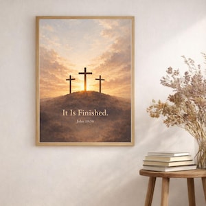 May include: Framed artwork featuring three black crosses on a hill, silhouetted against a sunset sky. The text "It Is Finished. John 19:30" is displayed below the crosses. The artwork is in a wooden frame.
