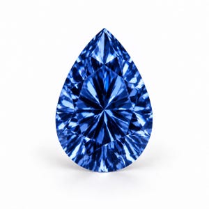 Puede incluir: Una piedra preciosa en forma de pera de color azul intenso con una superficie facetada. La piedra presenta una disposición simétrica de facetas triangulares y en forma de cometa que crean un patrón brillante y reflectante en toda la superficie.