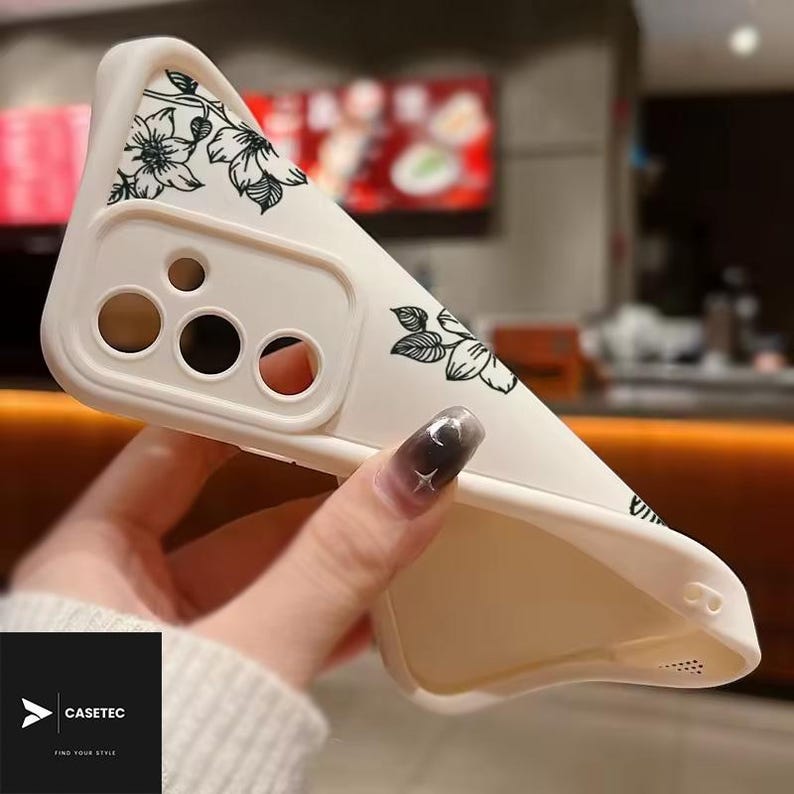May include: Off-white phone case with a floral design in black. The case has cutouts for the camera and other phone features. The brand name "CASETEC" is visible in a black square at the bottom left corner.