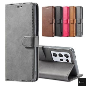 May include: A grey leather phone case with a magnetic clasp and stitching detail. The case is shown in various colours, including brown, black, pink, and grey. The phone case is designed to protect the phone and can be folded to act as a stand.