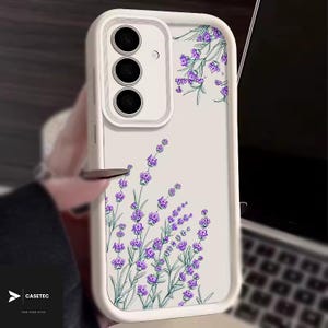 May include: White phone case with a floral lavender design. The case features a clear back with purple lavender flowers and green stems. The case has a white border and a camera cutout.