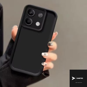 May include: A black phone case with a camera lens protector. The case has a matte finish and a raised edge around the camera. The phone case is being held by a person. The brand name "CASETEC" is visible in the bottom right corner.