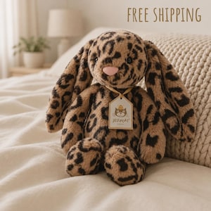 Könnte beinhalten: Ein Plüschtier in Form eines Hasen mit langen Ohren, bedeckt mit einem braun-schwarzen Leopardenmuster. Der Hase hat eine weiche rosa Nase und ein kleines Etikett um den Hals, auf dem Jellycat London mit einem Katzensymbol steht.