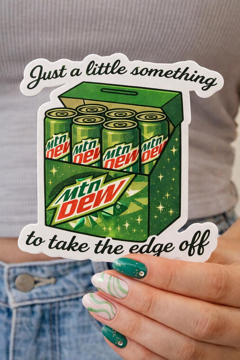 May include: A sticker depicting a green box containing six Mtn Dew cans. The box has the Mtn Dew logo and the text "Just a little something to take the edge off."