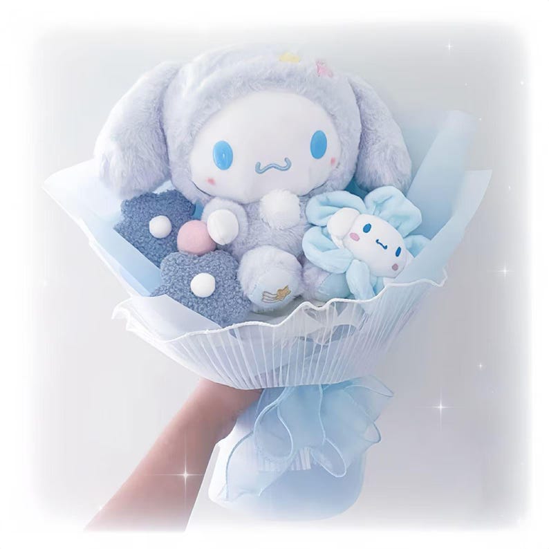 May include: A plush bouquet featuring a light blue Cinnamoroll character doll with a hood, surrounded by blue plush flowers and star-shaped accents. The bouquet is wrapped in light blue paper and tied with a matching ribbon.