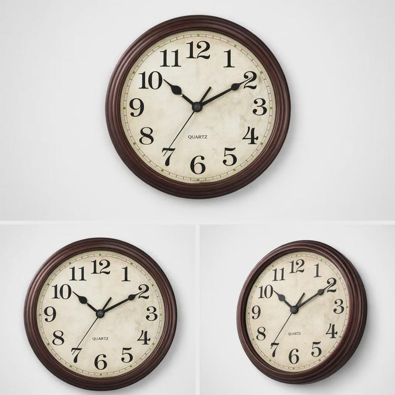 May include: A round wall clock with a dark brown frame and a cream-colored face. The clock features black numerals and hands, with the word "QUARTZ" printed below the center. The clock is approximately 10 inches in diameter.