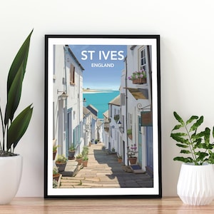 Może przedstawiać: Oprawiony wydruk artystyczny przedstawiający St Ives w Anglii, z wąską uliczką prowadzącą do oceanu. Grafika przedstawia białe budynki z niebieskimi akcentami, rośliny doniczkowe i napis "ST IVES ENGLAND" u góry.