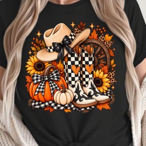 Puede incluir: Una camiseta negra con un estampado gráfico de un sombrero de vaquero beige con un lazo negro, botas de vaquero a cuadros blancos y negros con corazones naranjas, calabazas naranjas con un lazo a cuadros, girasoles y una rueda de carreta.