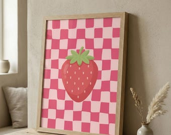 Può includere: Stampa incorniciata con un'illustrazione stilizzata di fragola. La fragola è rossa con semi bianchi e un gambo verde. Lo sfondo è un motivo a scacchiera rosa e rosa chiaro, il tutto all'interno di una cornice in legno chiaro.