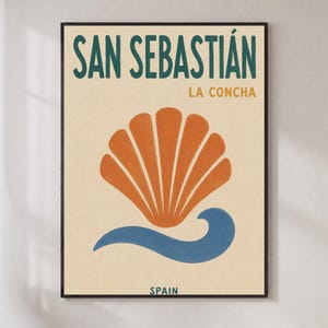 以下が含まれることがあります： SAN SEBASTIÁN LA CONCHAおよびSPAINの文字が入った額装アートプリント。クリーム色の背景に、大きなオレンジ色の貝殻のグラフィックと、その下に配置された青い波の形が描かれています。