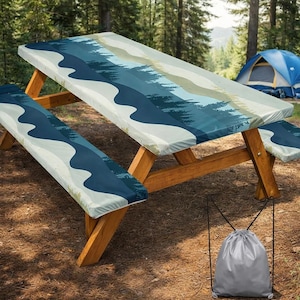 以下が含まれることがあります： テーブルトップとベンチに青と白の山脈のデザインが施された木製のピクニックテーブル。テーブルは屋外にあり、背景にはテントがあります。灰色の巾着袋が近くにぶら下がっています。