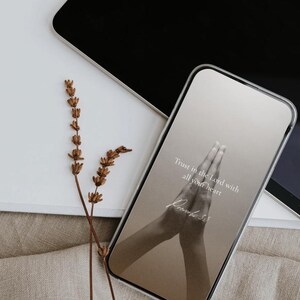 May include: A smartphone with a clear case shows a screen with the text "Trust in the Lord with all your heart" and a graphic of praying hands. Dried lavender sprigs and a tablet are also visible.