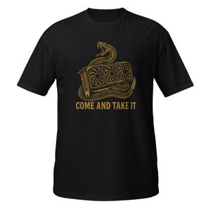 May include: A black short-sleeve t-shirt featuring a gold-colored graphic of a coiled rattlesnake wrapped around a triple-fan computer graphics card. Below the illustration, the text "COME AND TAKE IT" is printed in a bold, gold-colored font.