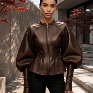 May include: A dark brown faux leather jacket featuring a high collar, a full-length front zipper, and voluminous puff sleeves that taper into long, fitted cuffs. The garment has a cinched waistline and structured seams along the bodice.