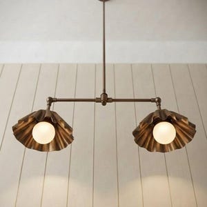 May include: A bronze-toned metal pendant light fixture featuring a central rod suspended from a circular ceiling mount. The fixture has two horizontal arms, each ending in a scalloped, shell-shaped shade containing a round, frosted white light bulb.