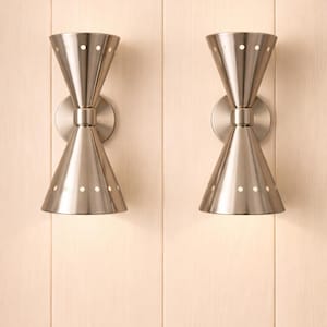 May include: A pair of wall-mounted sconces featuring a double-cone design in a brushed metallic finish. Each fixture has a circular wall plate and a central cylindrical connector, with small circular perforations along the rims of both cones.