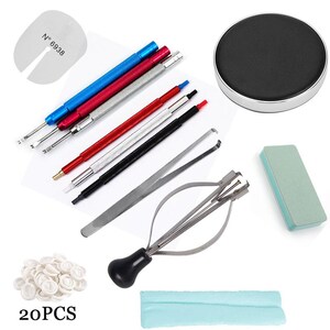 May include: A collection of watch repair tools, including screwdrivers with blue, red, and black handles, tweezers, a black watch holder, a green polishing block, and finger cots. The image also includes a spring bar tool and a cleaning cloth.