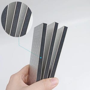 A hand holding three rectangular metallic objects with a textured surface.