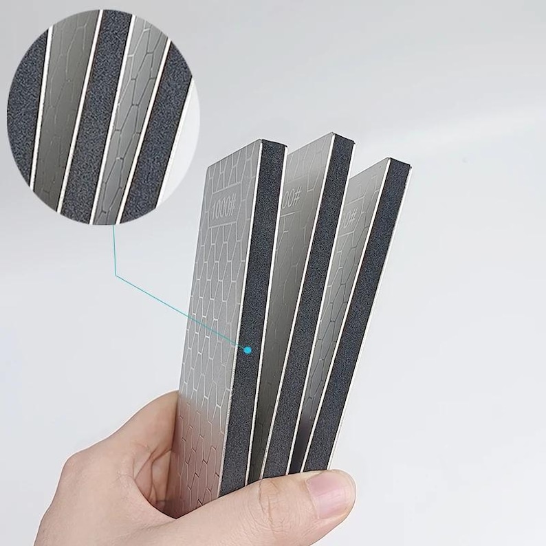 A hand holding three rectangular metallic objects with a textured surface.