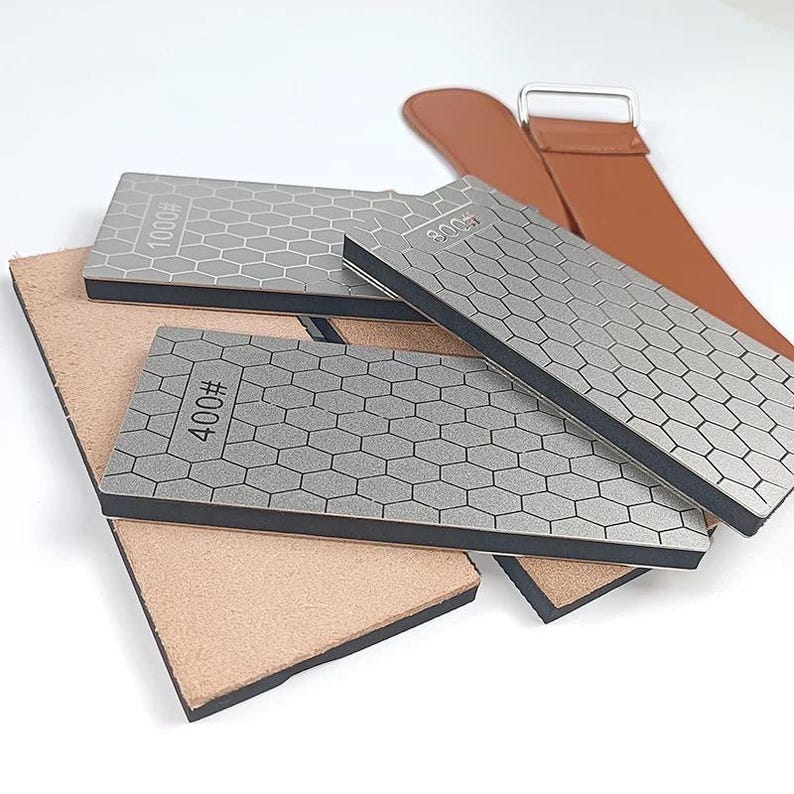 a collection of various items, including a leather belt, a metal file, and a small rectangular object with a hexagonal pattern.