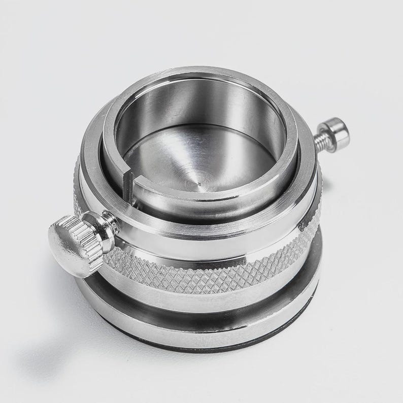 a close-up view of a metal object with a circular opening and two knobs on either side.