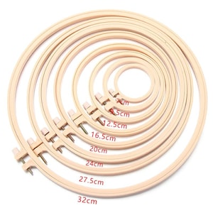 May include: A collection of wooden embroidery hoops in various sizes, ranging from 7 cm to 32 cm in diameter. Each hoop features a screw mechanism for securing fabric. The natural wood color provides a classic look for needlework projects.