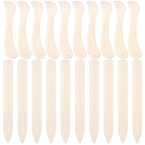 May include: A collection of twenty off-white tools arranged in two rows. The top row features ten curved bone folders with a small hole at the base. The bottom row consists of ten straight, pointed creasing tools with a smooth, solid surface.