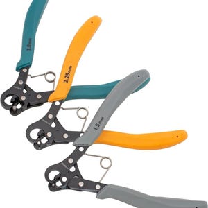 May include: Three wire strippers with black metal bodies and colored handles. The handles are teal, orange, and gray. Each tool has a different measurement printed on it: 3.0 mm, 2.25 mm, and 1.5 mm. The tools are designed for precision wire stripping.