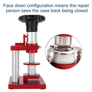 May include: A red and silver watch case closer tool with a black handle. The tool has a square base and a circular platform. The text in the image says "Face down configuration means the repair person sees the case back being closed."