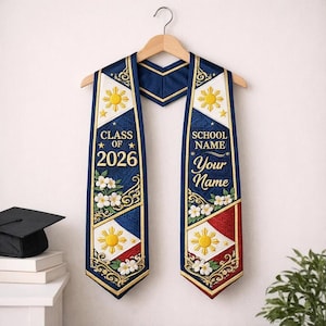 May include: A white ceramic mug with a black handle and the text "But First, Coffee" in a bold, black font. The mug is set against a blurred background, suggesting a cosy setting.