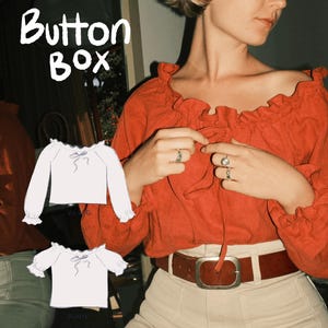 Könnte beinhalten: Eine Frau trägt eine rote Off-Shoulder-Bluse mit Rüschenkragen und einem braunen Gürtel. Das Bild enthält eine Skizze einer weißen Bluse mit langen Ärmeln und einer Schleife sowie eine weitere mit kurzen Ärmeln. Der Text "Button Box" steht oben.