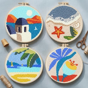 Könnte beinhalten: Vier runde Stickrahmen mit Strand- und Küstenszenen. Einer zeigt ein weißes Gebäude mit blauem Dach, orangefarbenen Bergen und blauem Meer. Ein anderer zeigt einen Seestern, Wellen und Sand. Die anderen beiden zeigen Palmen und Blumen.