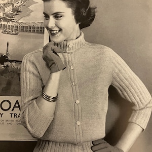 May include: A vintage-style light beige cardigan with a ribbed texture, button closure, and a high collar. The cardigan is worn with matching gloves and a silver bracelet. The image has a retro aesthetic.