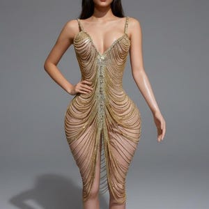 以下が含まれることがあります： 深いVネックとスパゲッティストラップが付いた、膝丈のゴールドカラーのドレス。 ドレスは、ドレープ効果を生み出すカスケードチェーンで作られています。 フォーマルなイベントに適した、フィットしたボディスとフレアスカートを備えています。