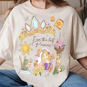 Op de afbeelding: Crèmekleurig T-shirt met een kleurrijke afbeelding van een prinses, een kroon en de tekst "I am the lost Princess!". Het ontwerp bevat een zon, een toren en lantaarns. Het shirt heeft een relaxte pasvorm.