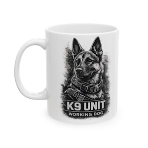 May include: White ceramic mug with a black and white illustration of a K9 unit dog. The dog is wearing a harness and collar. The text "K9 UNIT WORKING DOG" is printed below the dog.