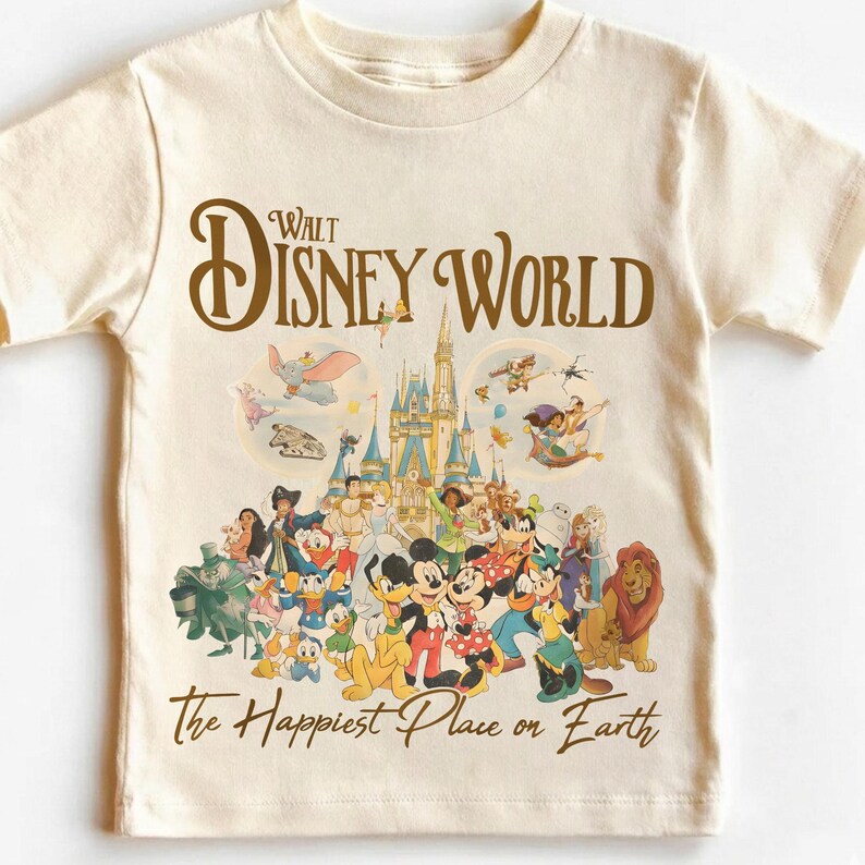 May include: Cream-colored t-shirt featuring a graphic of Disney World characters and the text "Walt Disney World" in brown. The shirt also includes the phrase "The Happiest Place on Earth" in a script font.