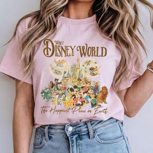 May include: A light pink t-shirt featuring a colorful graphic of Disney characters, including Mickey Mouse, Minnie Mouse, and Simba. The text "Walt Disney World" and "The Happiest Place on Earth" are printed above and below the graphic.