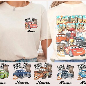 May include: Cream-colored t-shirt featuring a Cars movie design. The front has a small graphic of Lightning McQueen with flags. The back displays a larger design with various Cars characters and the text "Radiator Springs".