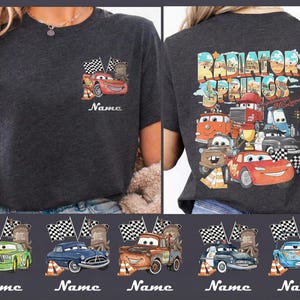 May include: Dark gray t-shirt featuring a colorful graphic of characters from the movie Cars. The front of the shirt shows Lightning McQueen with the word "Name" below. The back of the shirt has the words "Radiator Springs" and more characters.