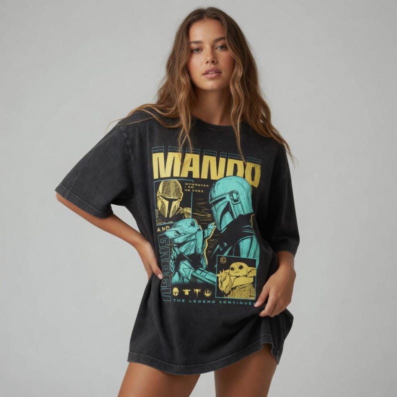 以下が含まれることがあります： マンダロリアンとグローグのグラフィックが特徴の黒いTシャツ。「MANDO」の文字が黄色のブロック体で、フレーズ「THE LEGEND CONTINUES」がデザインされています。このシャツは半袖で、ゆったりとしたフィット感です。