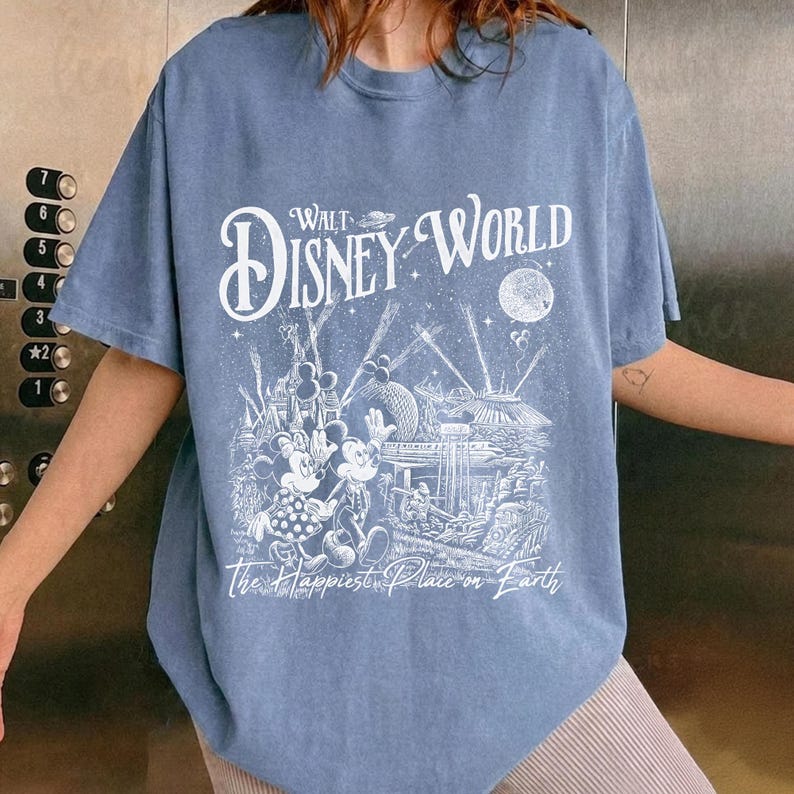 May include: Blue t-shirt featuring a white graphic of Walt Disney World with Mickey and Minnie Mouse. The text "Walt Disney World" and "The Happiest Place on Earth" are also printed on the shirt.