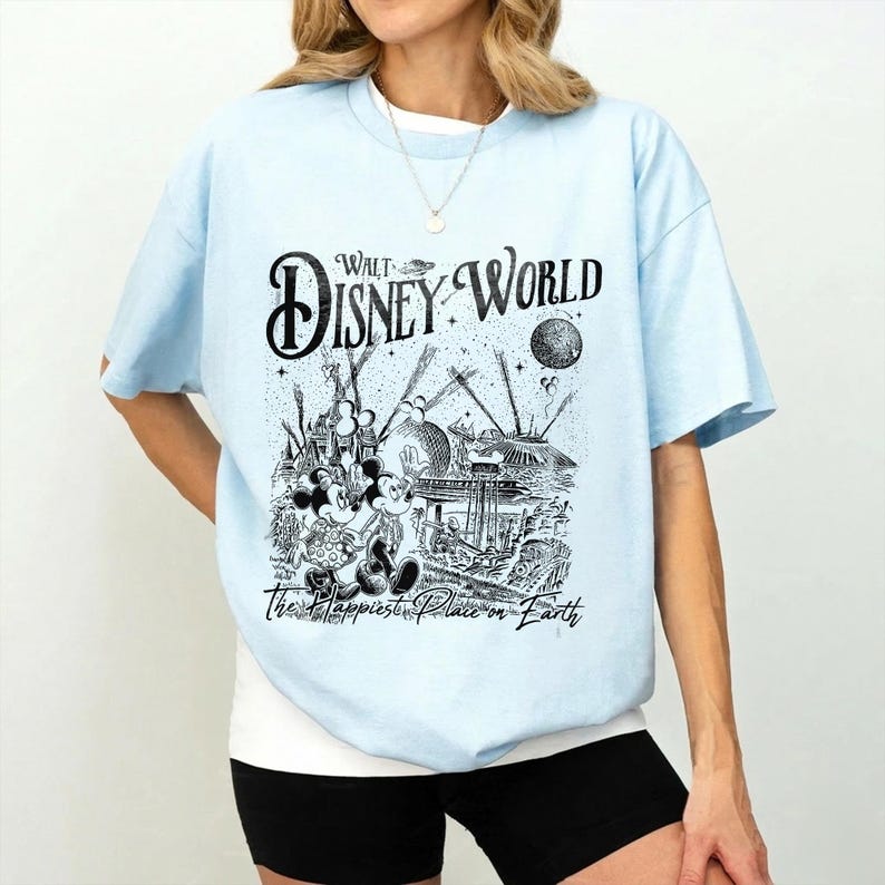May include: Light blue t-shirt featuring a black and white graphic of Mickey and Minnie Mouse, with the text "Walt Disney World" and "The Happiest Place on Earth". The shirt has short sleeves and a crew neck.
