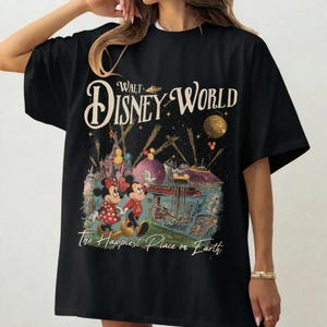 May include: Black t-shirt featuring a colorful graphic of Mickey and Minnie Mouse at Disney World. The design includes the text "Walt Disney World" and "The Happiest Place on Earth" in a vintage style. The shirt is a classic crew neck.